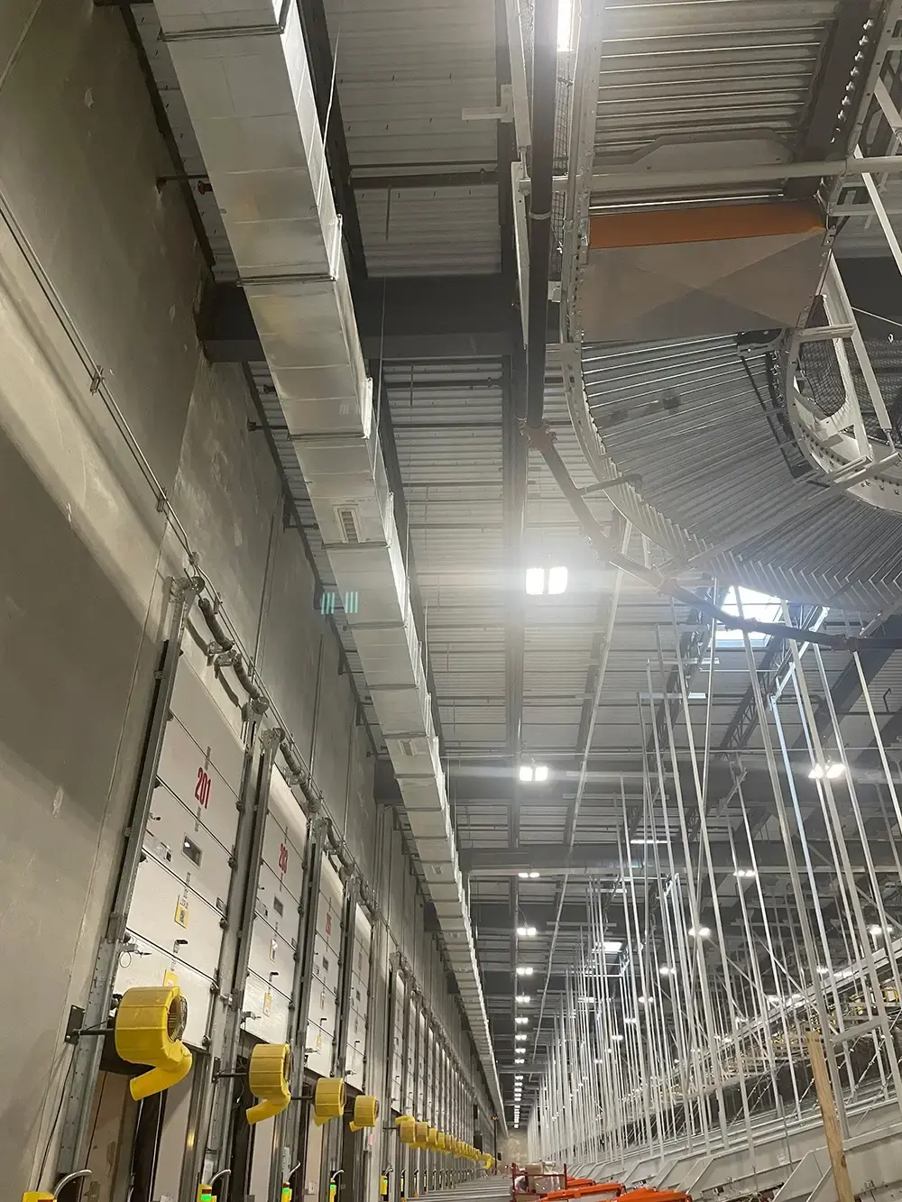 Warehouse interior with overhead ductwork, loading bay doors, and industrial lighting