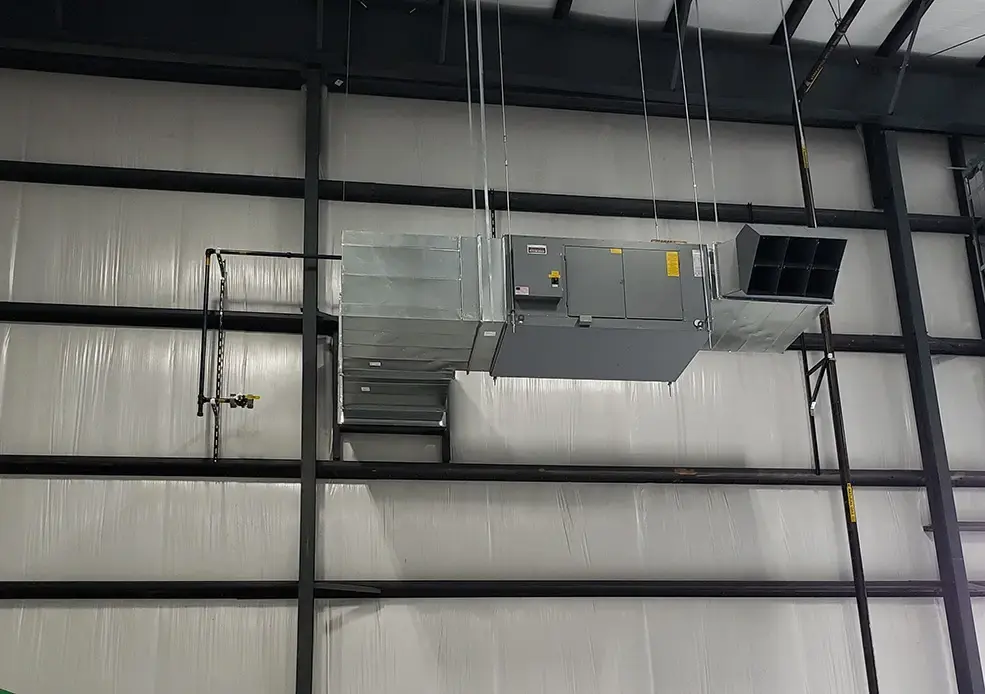 Ceiling-suspended HVAC unit with air handler and ductwork in an industrial building