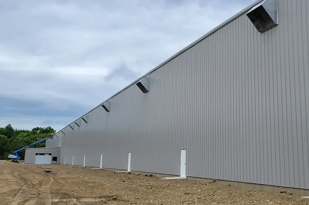 Exterior view of a large industrial building with ventilation units along the roofline