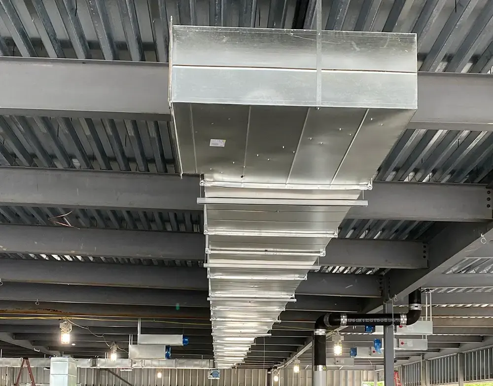 Industrial ceiling with large rectangular metal ductwork suspended along the beams