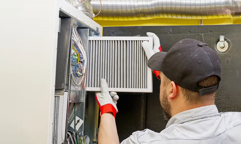 Technician installing filter in air conditioner